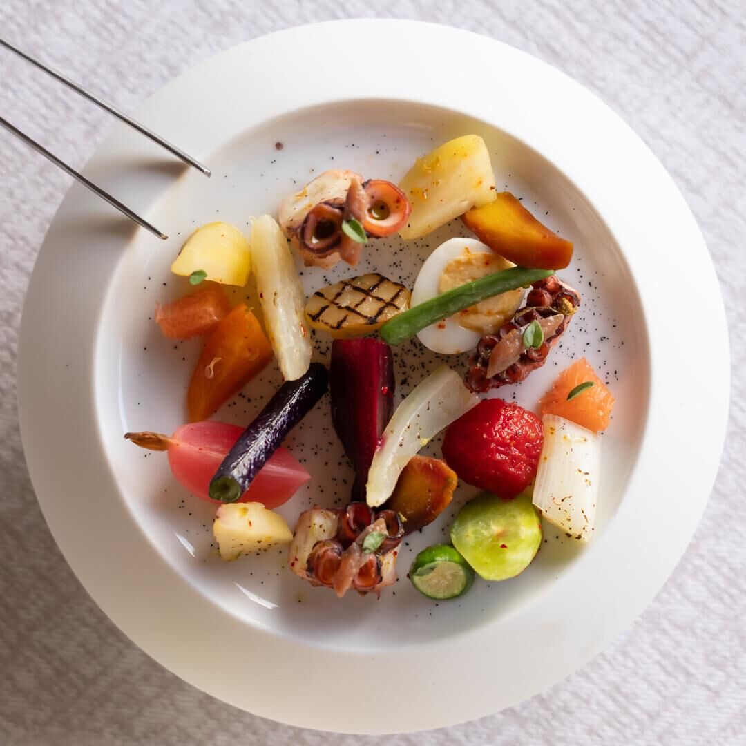 Assiette de légumes variés et d'éléments de fruits de mer présentés de manière artistique.