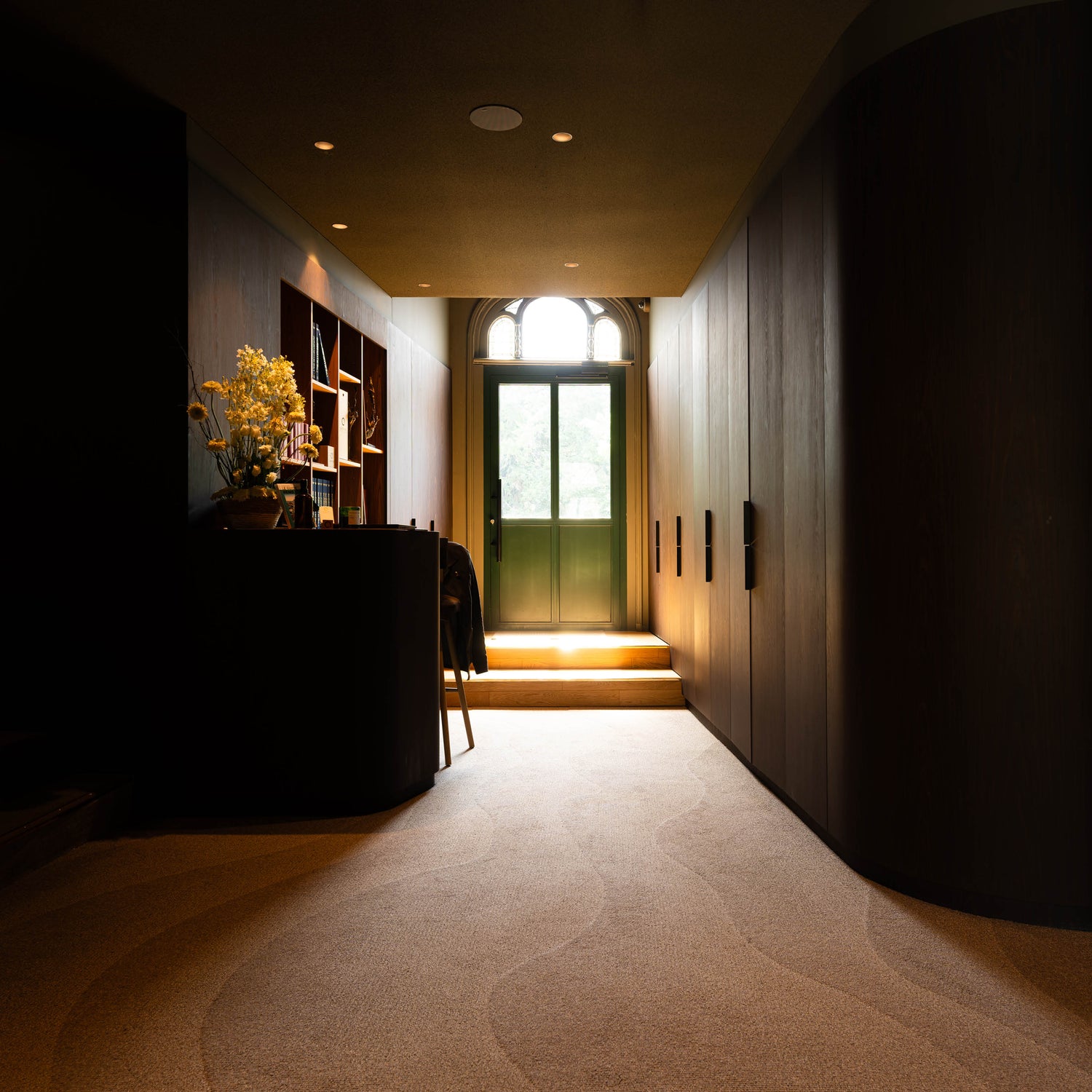 Couloir moderne avec éclairage doux et porte vitrée.