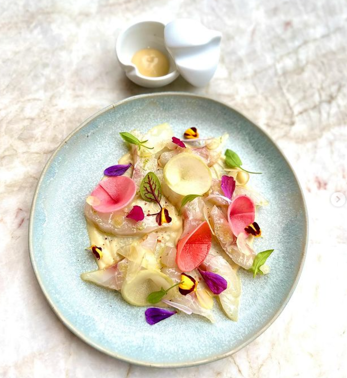 Plat élégant aux couleurs claires, poisson cru et mariné, betterave slicé et jeunes pousses