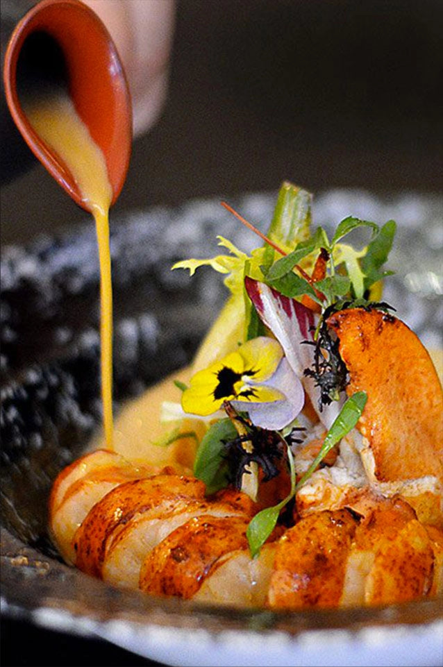 Plat gastronomique avec sauce et fleurs comestibles.