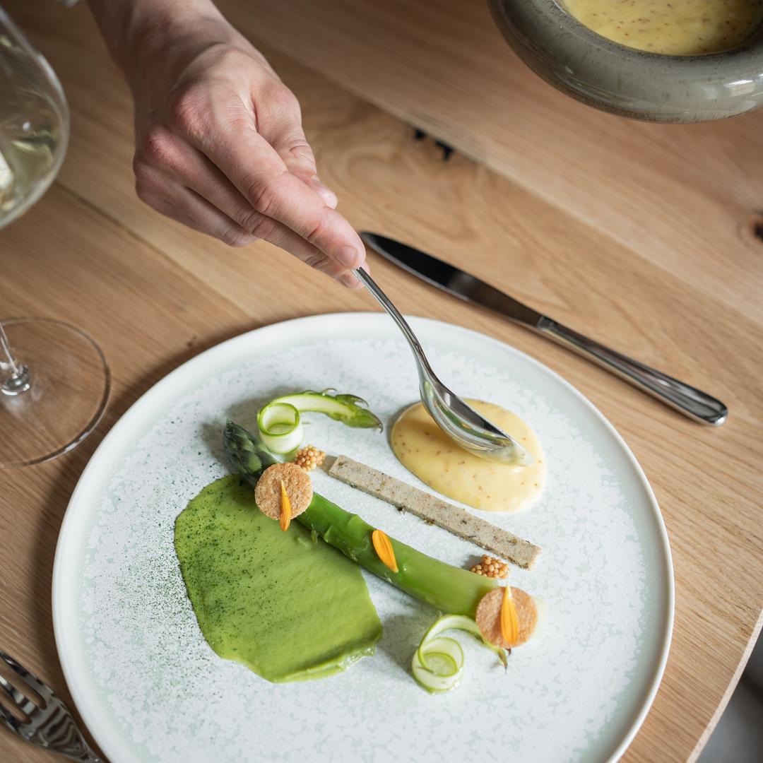 Plat gastronomique avec sauce, asperges et décorations.