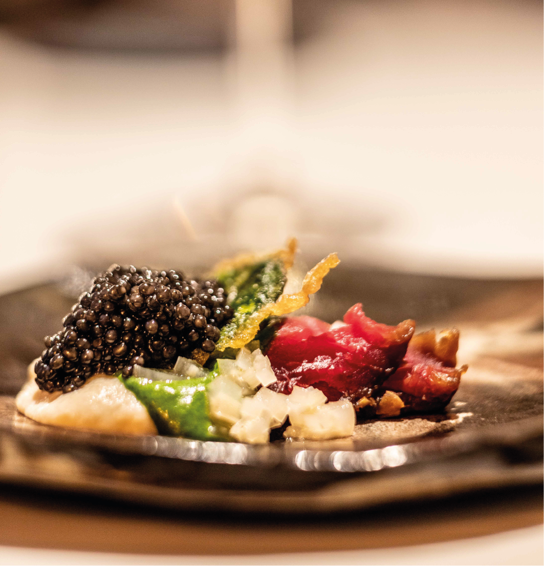 Entrée gastronomique composée de caviar, de viande rouge marinée, de petits légumes en julienne et d'une tuile croustilante