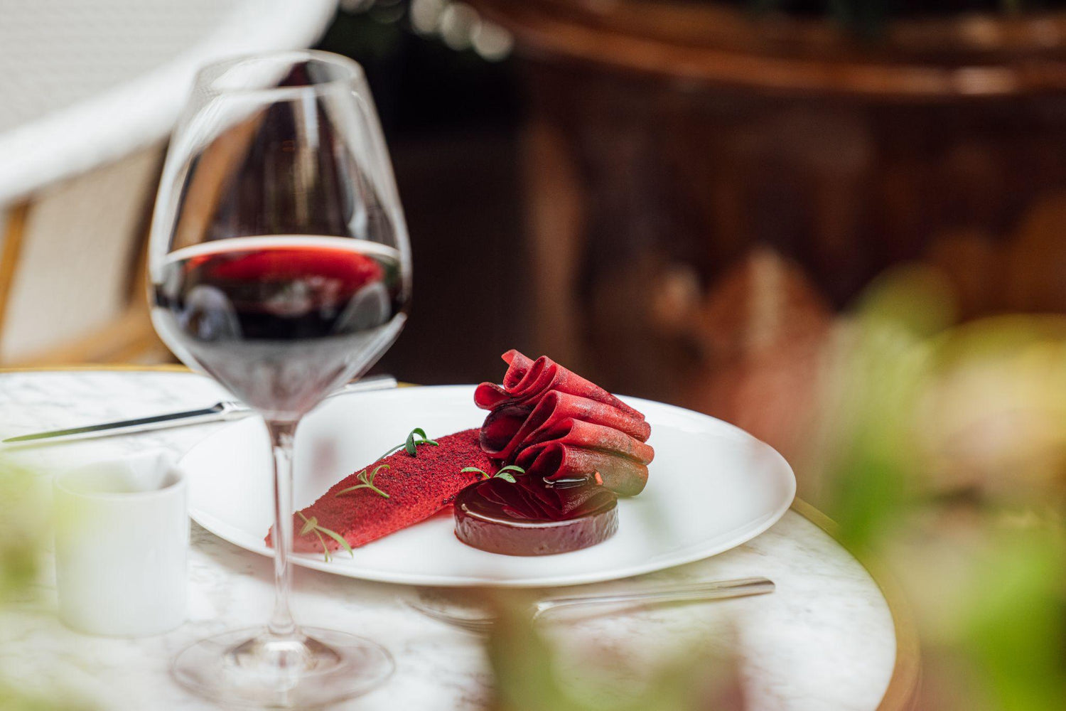 Dessert rouge sophistiqué avec un verre de vin rouge sur une table en marbre