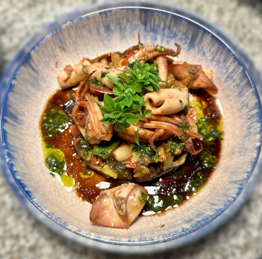 Plat de calamars servis avec une sauce et herbes fraîches au restaurant Le Bistro d'Hervé.