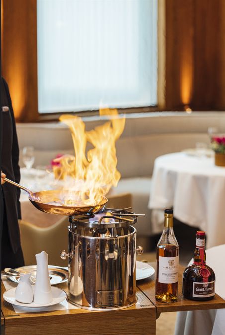 Flambage d'un plat avec des bouteilles d'alcool à côté, dans un restaurant