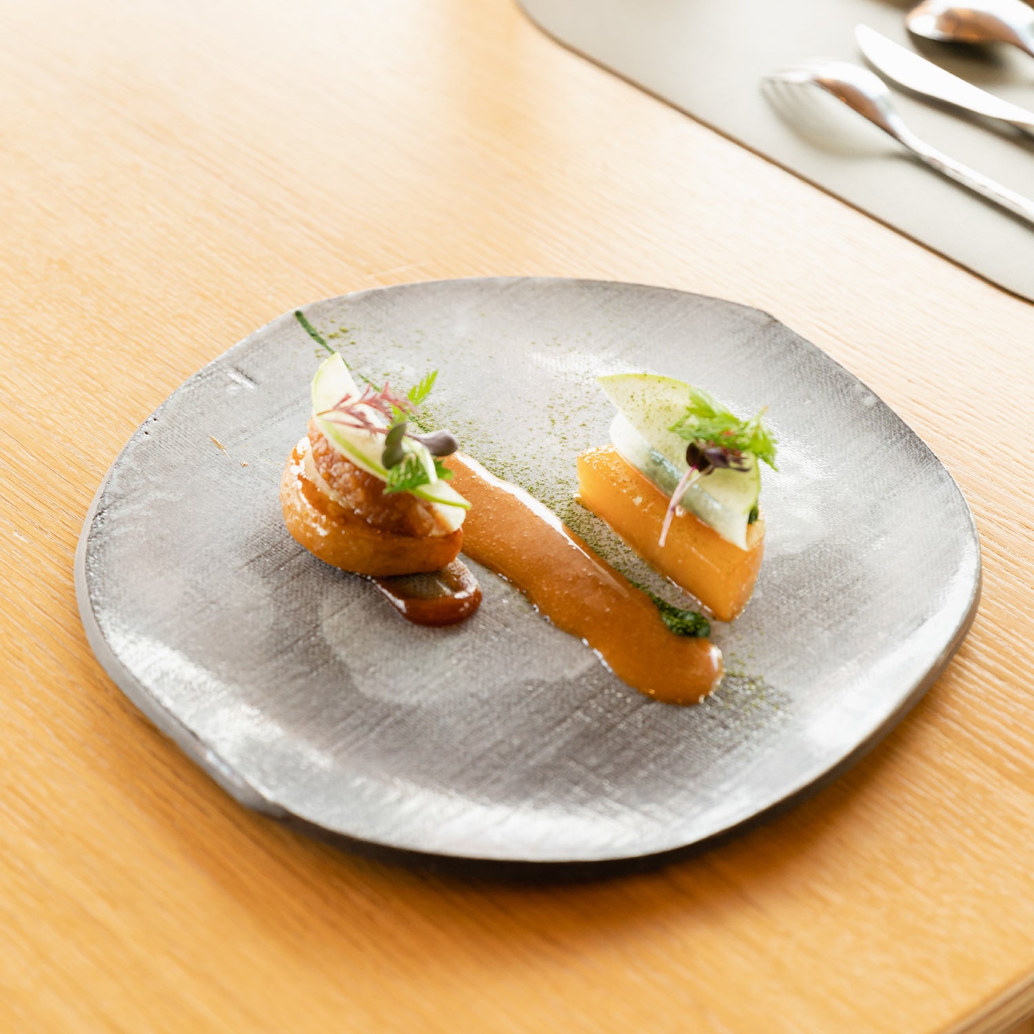 Assiette gastronomique élégante avec des morceaux de chou-rave finement disposés, nappés d'une sauce au vinaigre de cidre, garnis de fines herbes fraîches, présentée sur une table en bois clair dans un cadre raffiné.