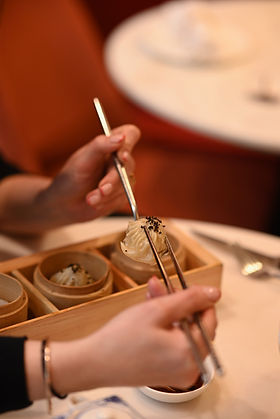 Person eating dumplings with chopsticks in a restaurant.