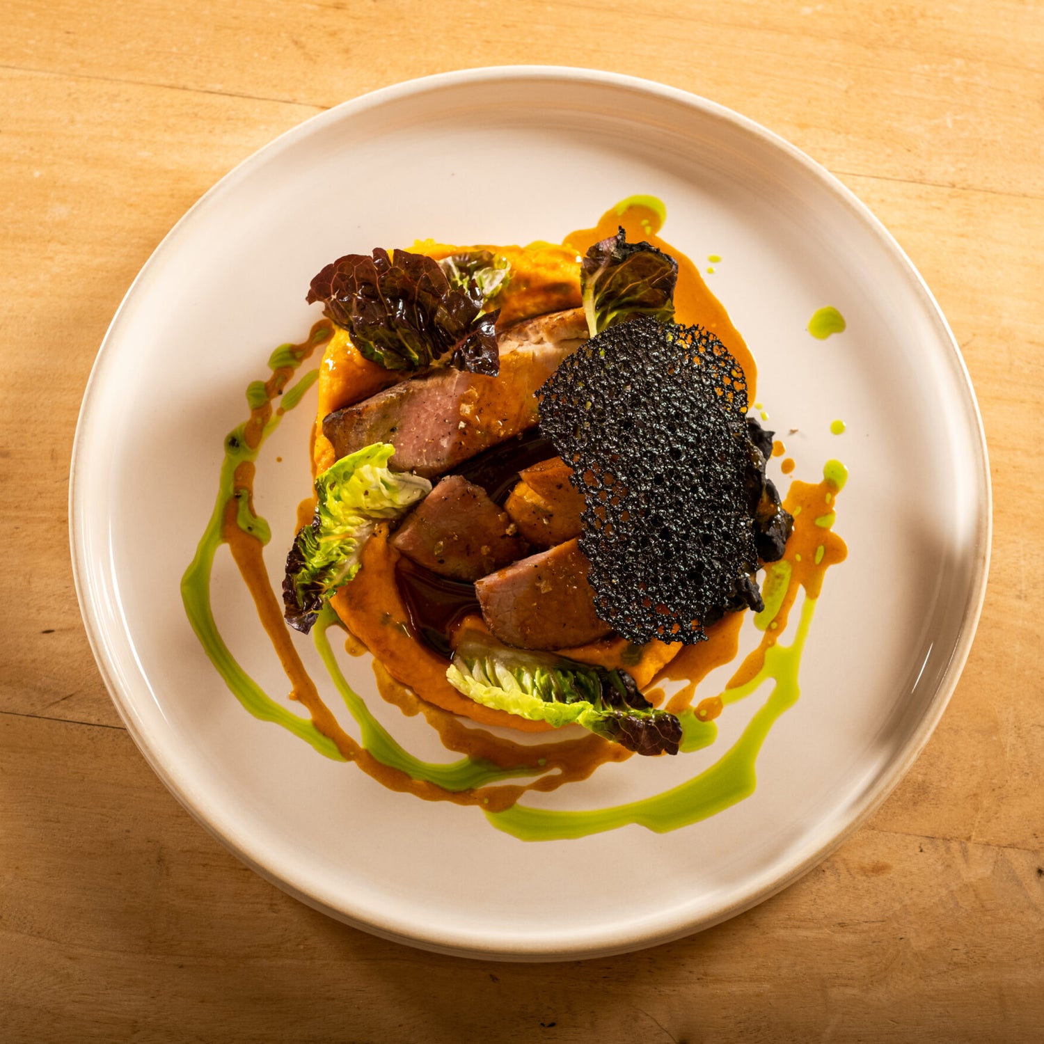 Plat gastronomique avec viande, légumes et sauce.
