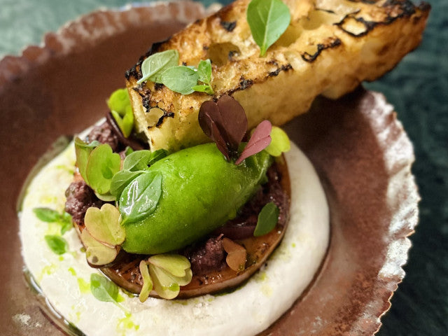 Plat gastronomique avec garniture verte et pain grillé.