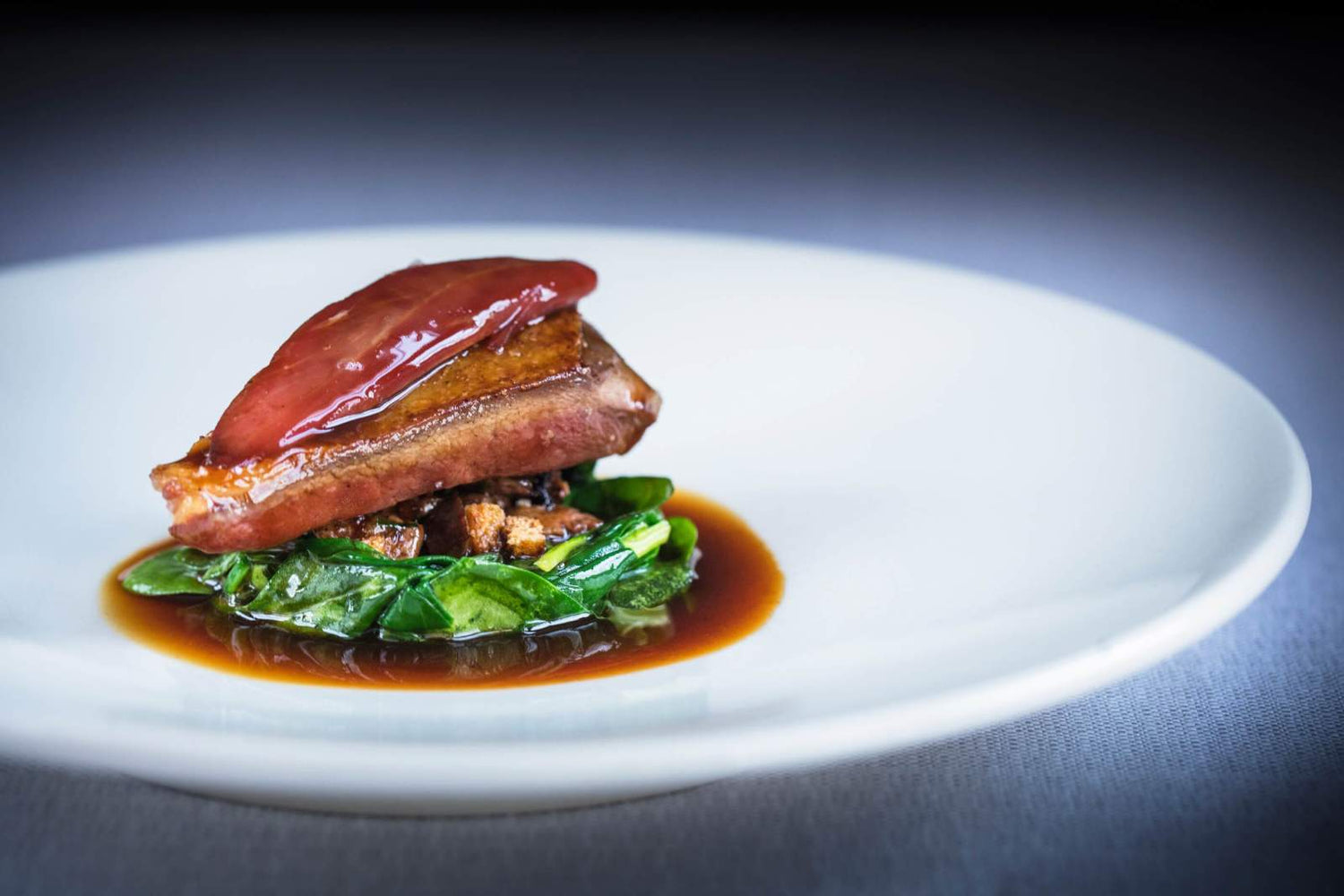 Filet de viande tendre servi sur un lit d'épinards et nappé de sauce brune.