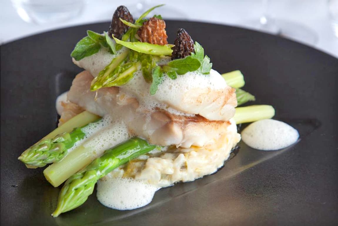Plat gastronomique avec poisson, asperges et mousse.