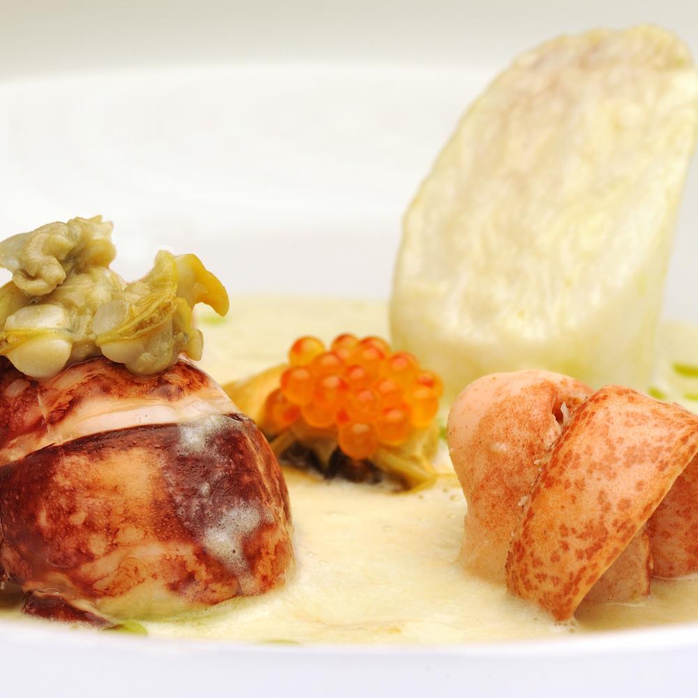 Plat gastronomique avec homard, œufs de poisson et sauce crémeuse, dans une présentation raffinée.