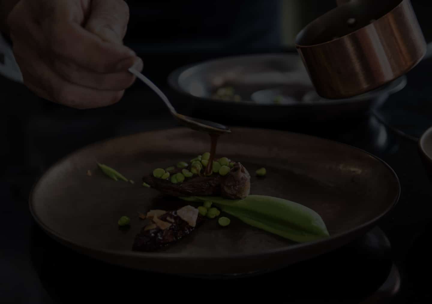 Personne versant une sauce sur un plat raffiné.
