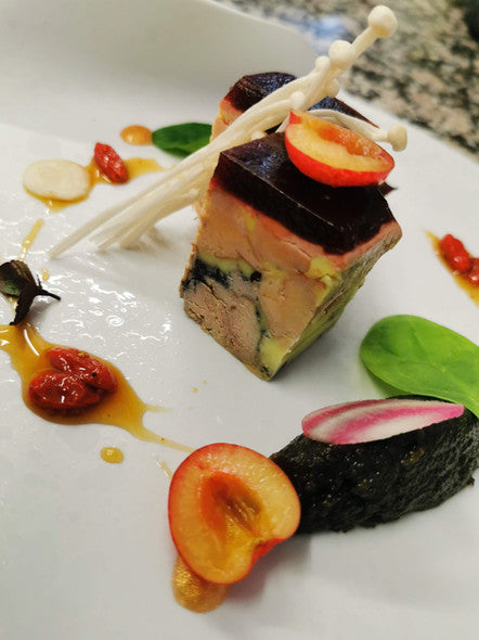 Plat de fruits de mer avec des légumes et une sauce mousseuse, présenté de manière artistique.