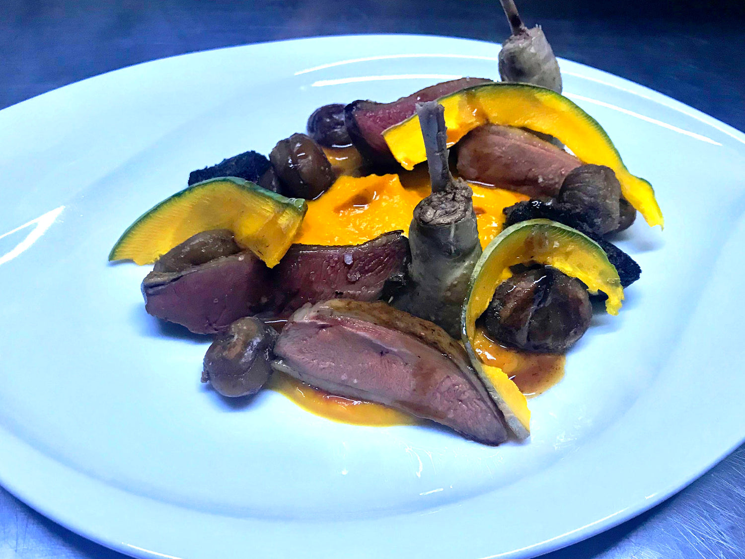 Magret de canard accompagné de citrouille et châtaignes dans une présentation gourmande.