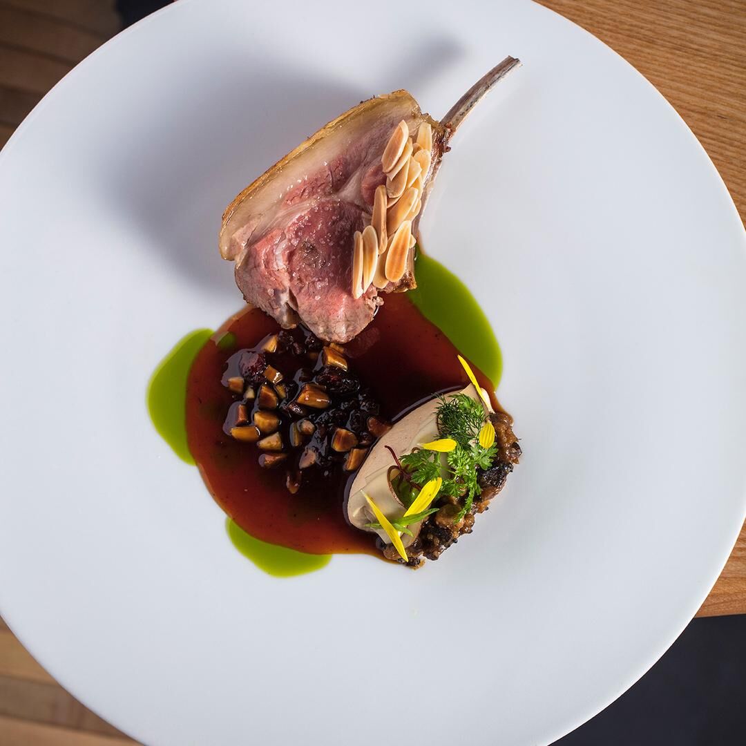 Plat de viande avec une sauce riche, des amandes effilées et des garnitures colorées.