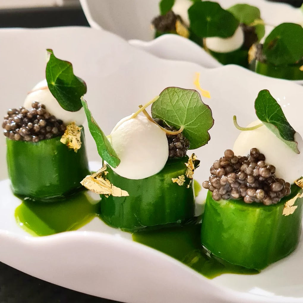 Plat gastronomique avec des endives caramélisées, garnies de truffes noires et d'autres éléments décoratifs.
