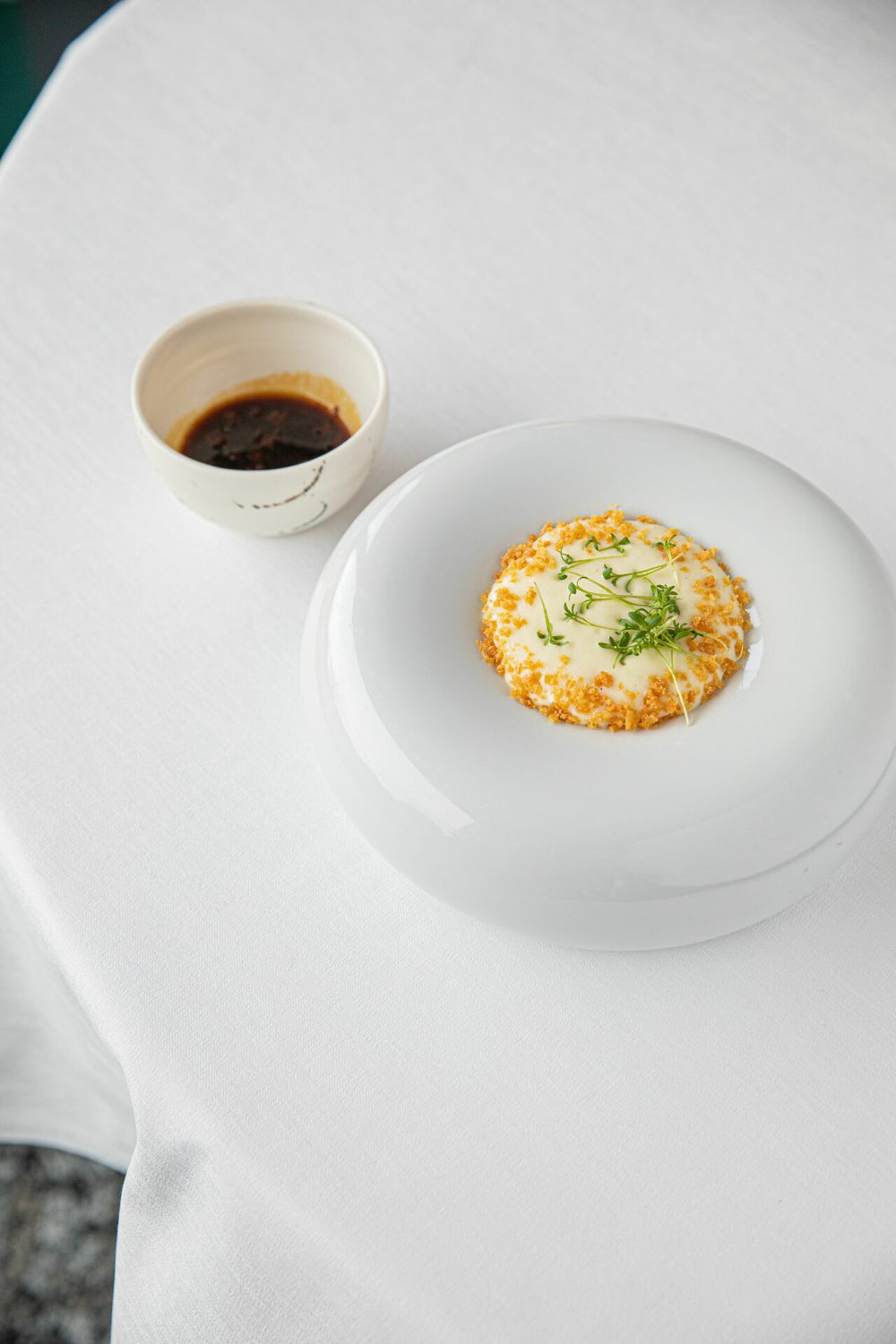Assiette élégante avec un plat composé de légumes verts et d'une mousse légère, accompagné d'une petite tasse de sauce à côté.