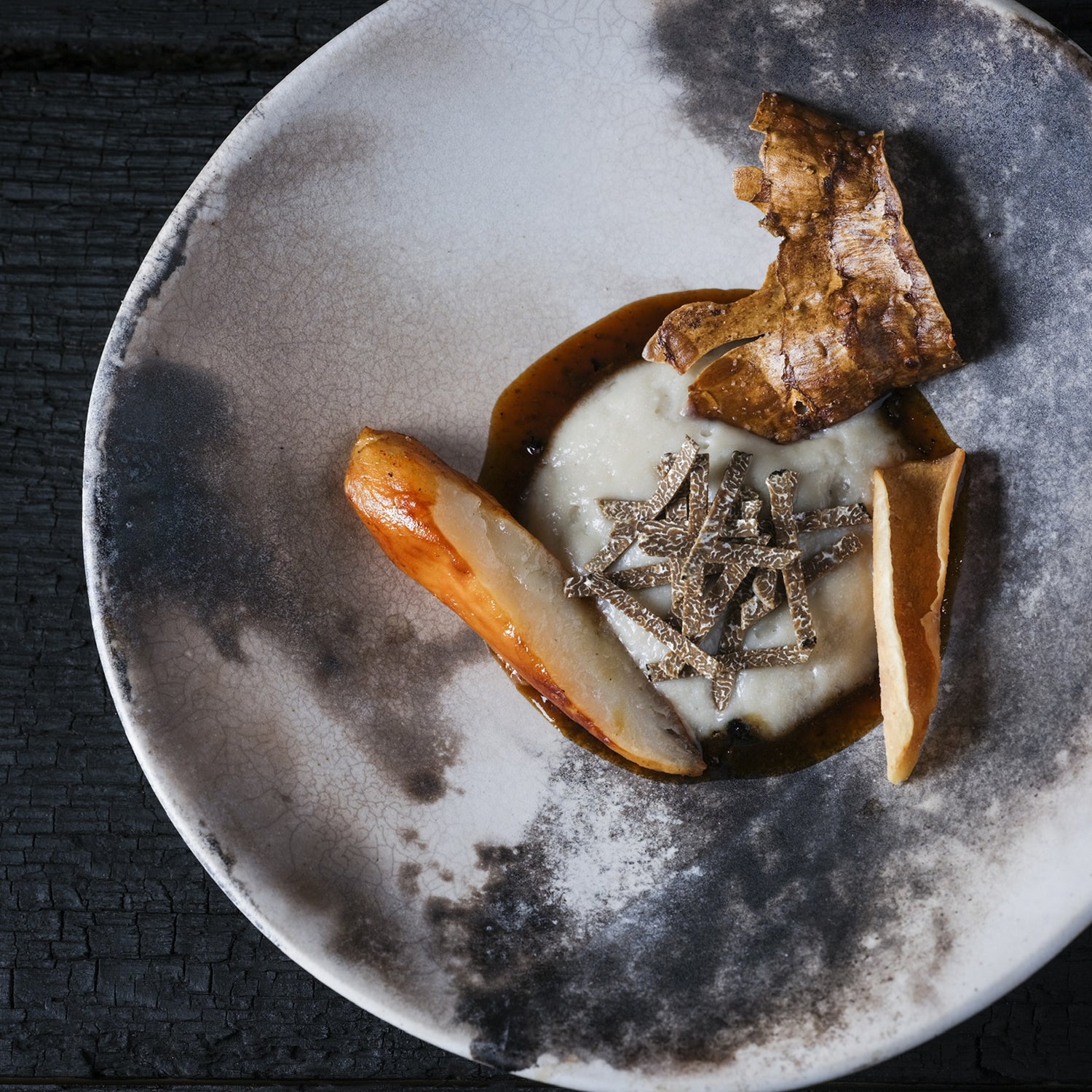 Assiette raffinée composée de racines d’héliantis, truffe d’Alsace et purée onctueuse, présentée sur une céramique texturée.