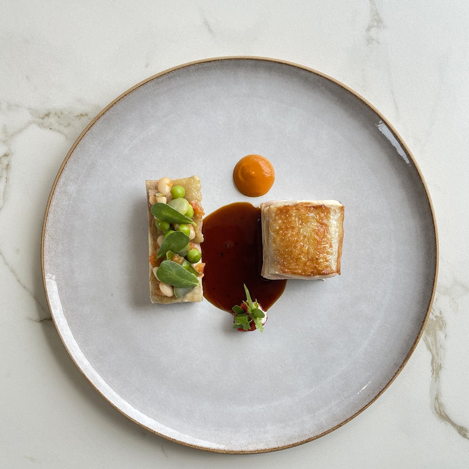 Plat gastronomique avec une présentation artistique sur une assiette blanche.
