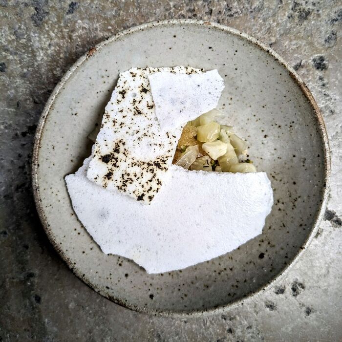 Assiette minimaliste avec des éclats blancs et une garniture élégante, servie au restaurant Épicéa.