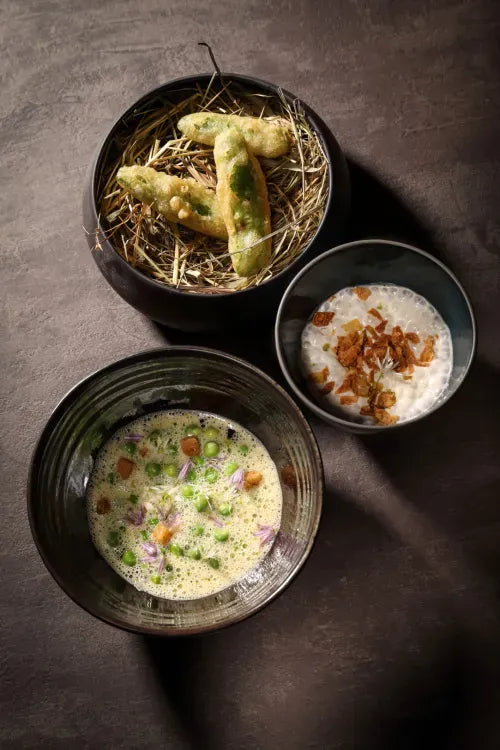 Présentation de plats gastronomiques avec tempura sur paille, soupe crémeuse aux herbes et crème garnie de miettes croustillantes