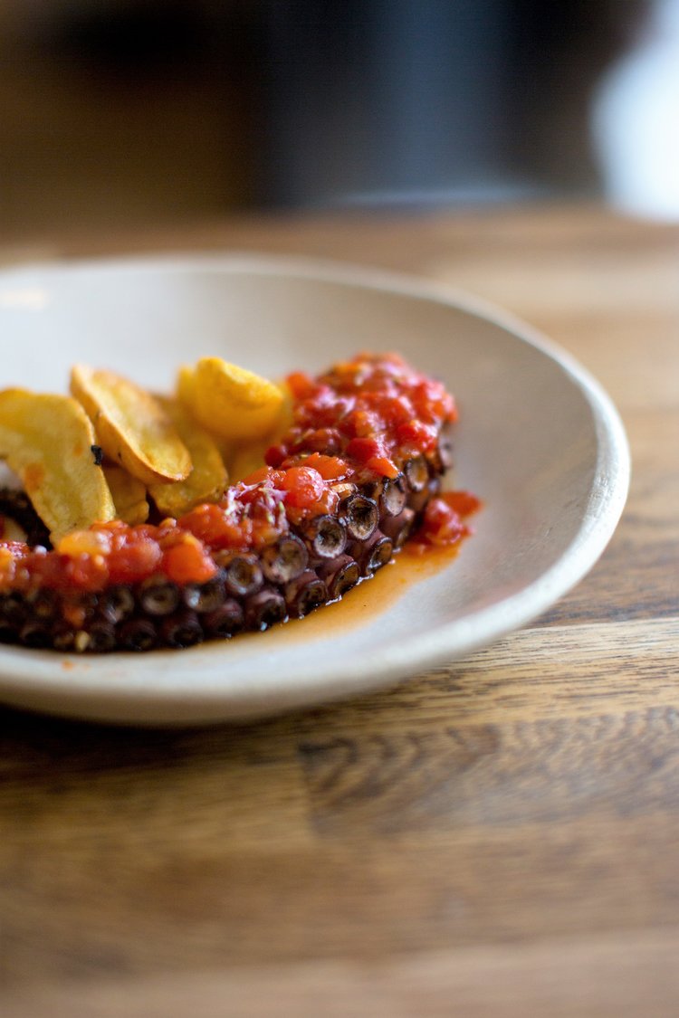 Plat de poulpe avec sauce tomate et chips.