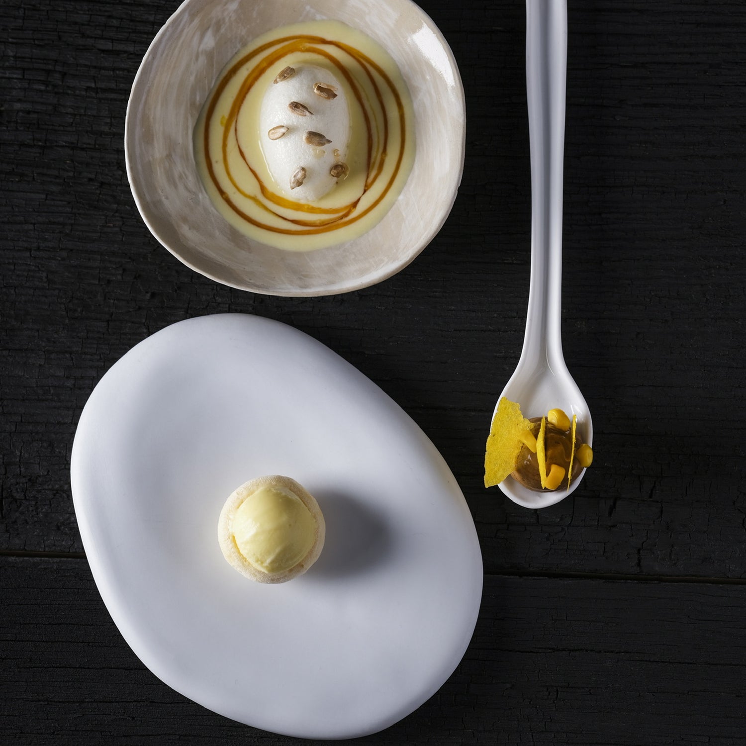Dessert créatif à base de maïs et de crème, présenté avec élégance dans des assiettes design sur fond noir.