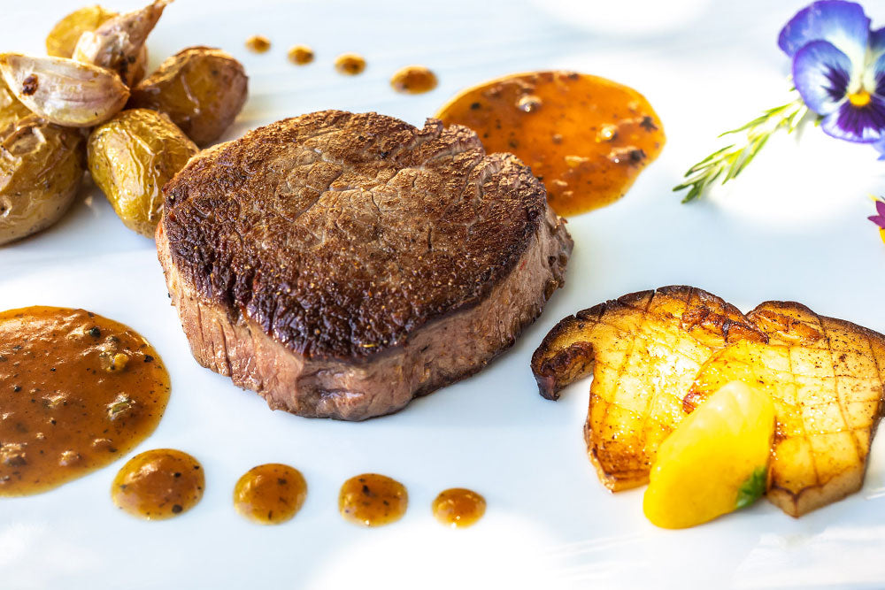 Pièce de bœuf cuite à la perfection, accompagnée de pommes de terre et de sauce.
