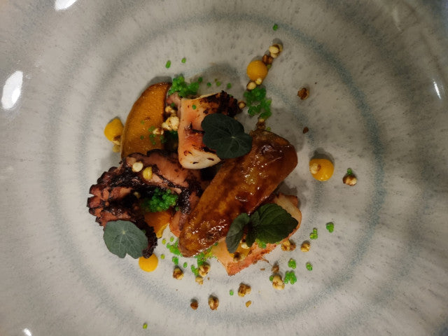 Plat gastronomique avec poulpe et légumes.