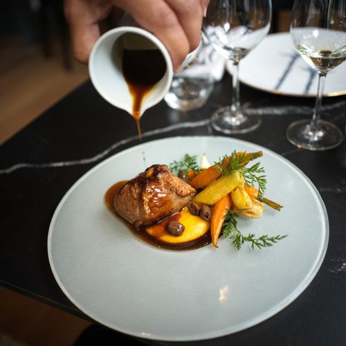 Une belle pièce de viande confite, purée de carotte, petites carottes confites, fane de carotte, jus de viande versé dessus