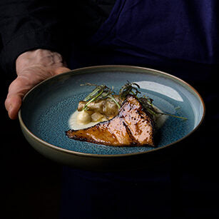 "Assiette élégante de poisson grillé, servie avec purée et garniture délicate dans un plat bleu."
