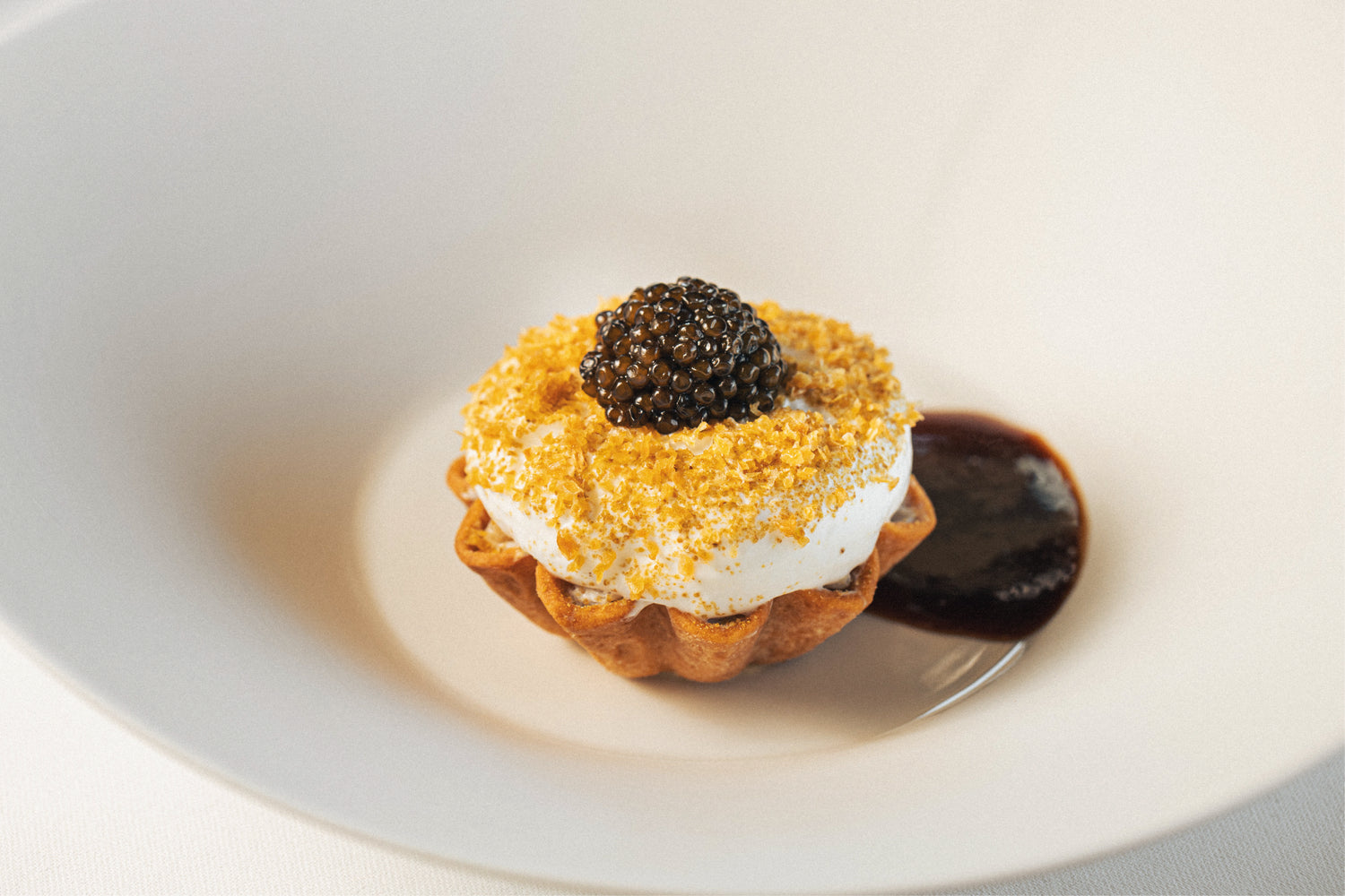 Dessert gastronomique raffiné garni de crème légère et surmonté d’une touche gourmande, présenté dans une assiette blanche.