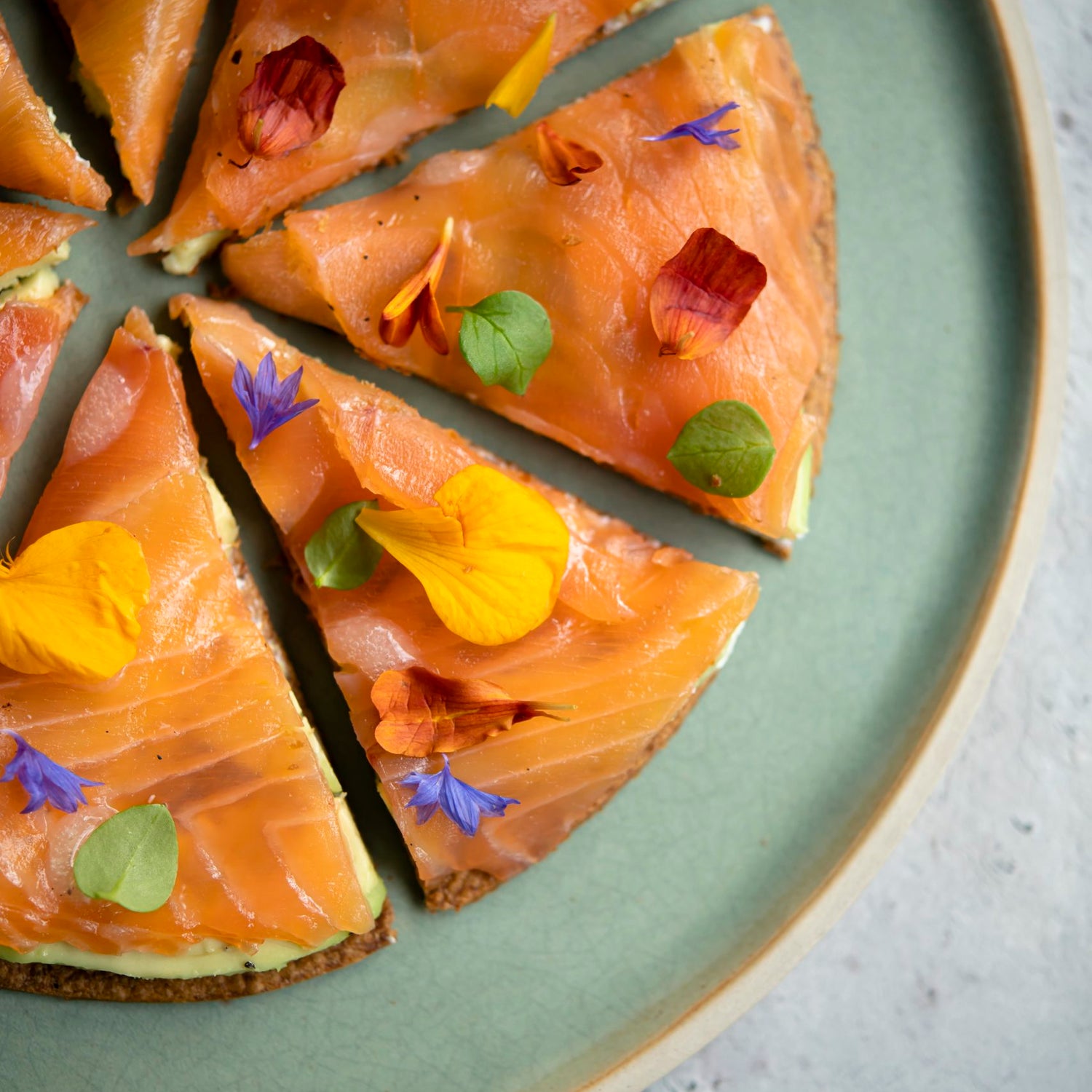 Entrée composée d'une fine tuile, crème d'avocat, saumon fumé et fleurs comestibles