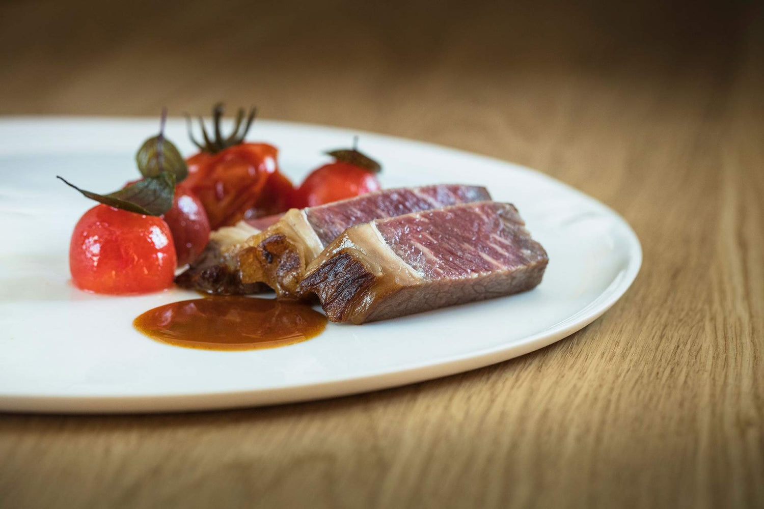 De beaux morceaux de viande saignants, des tomates cerises rôties et un jus de viande