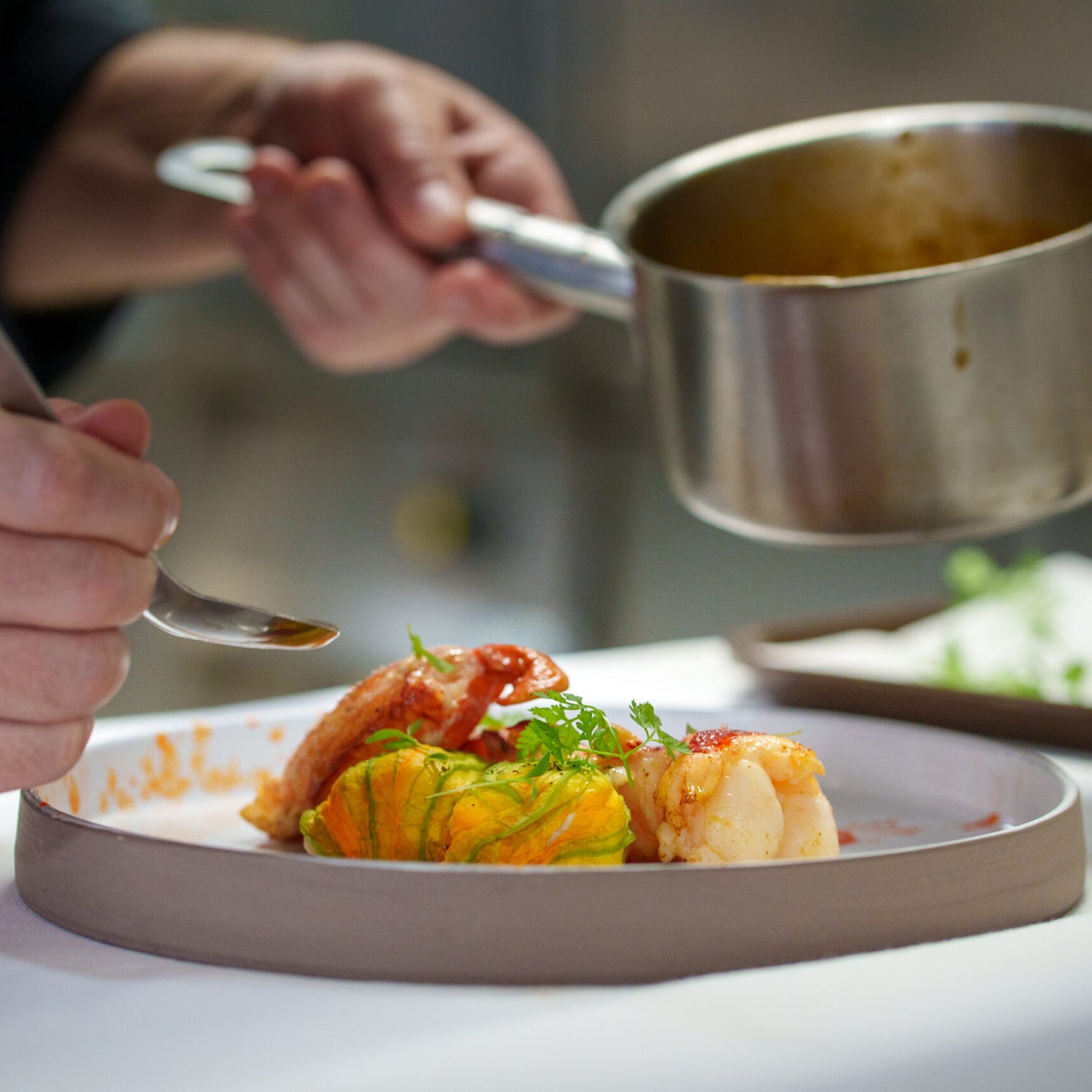 Chef apportant la touche finale à un plat de langouste et de fleur de courgette farcie