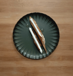 "Élégants bâtonnets de chocolat blanc et caramel posés sur un plat noir moderne, un dessert raffiné."