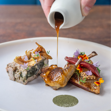 Viande gourmet avec sauce versée et accompagnements créatifs dans une assiette moderne.






