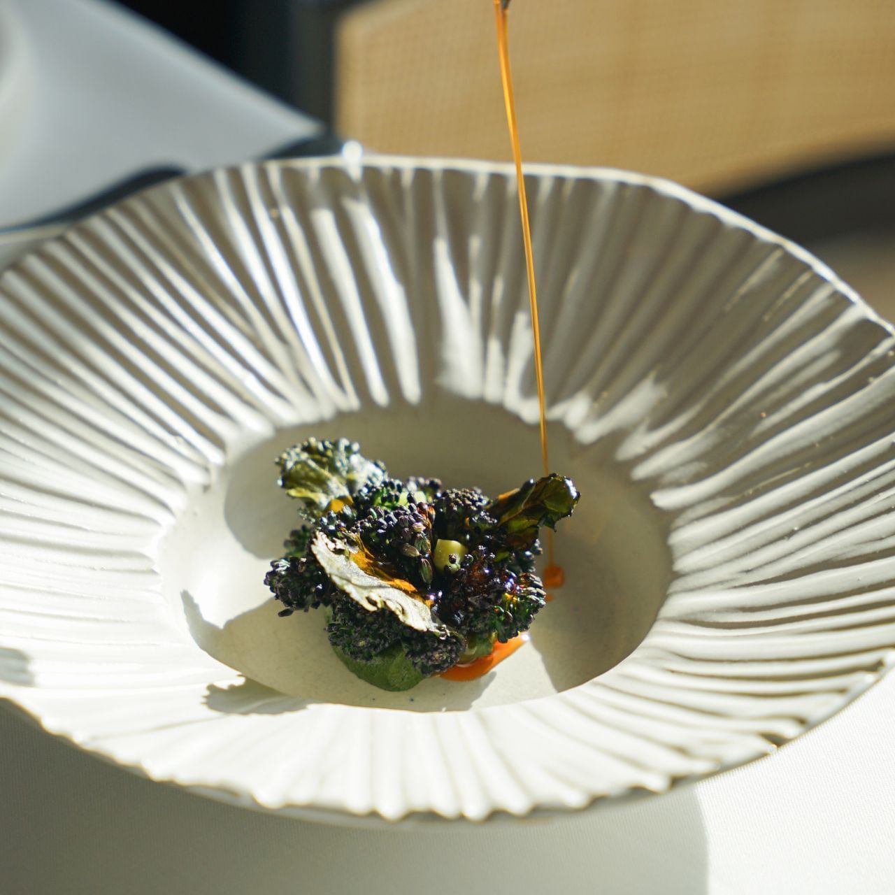 Un plat de brocoli avec une sauce versée dessus, présenté dans une assiette élégante.