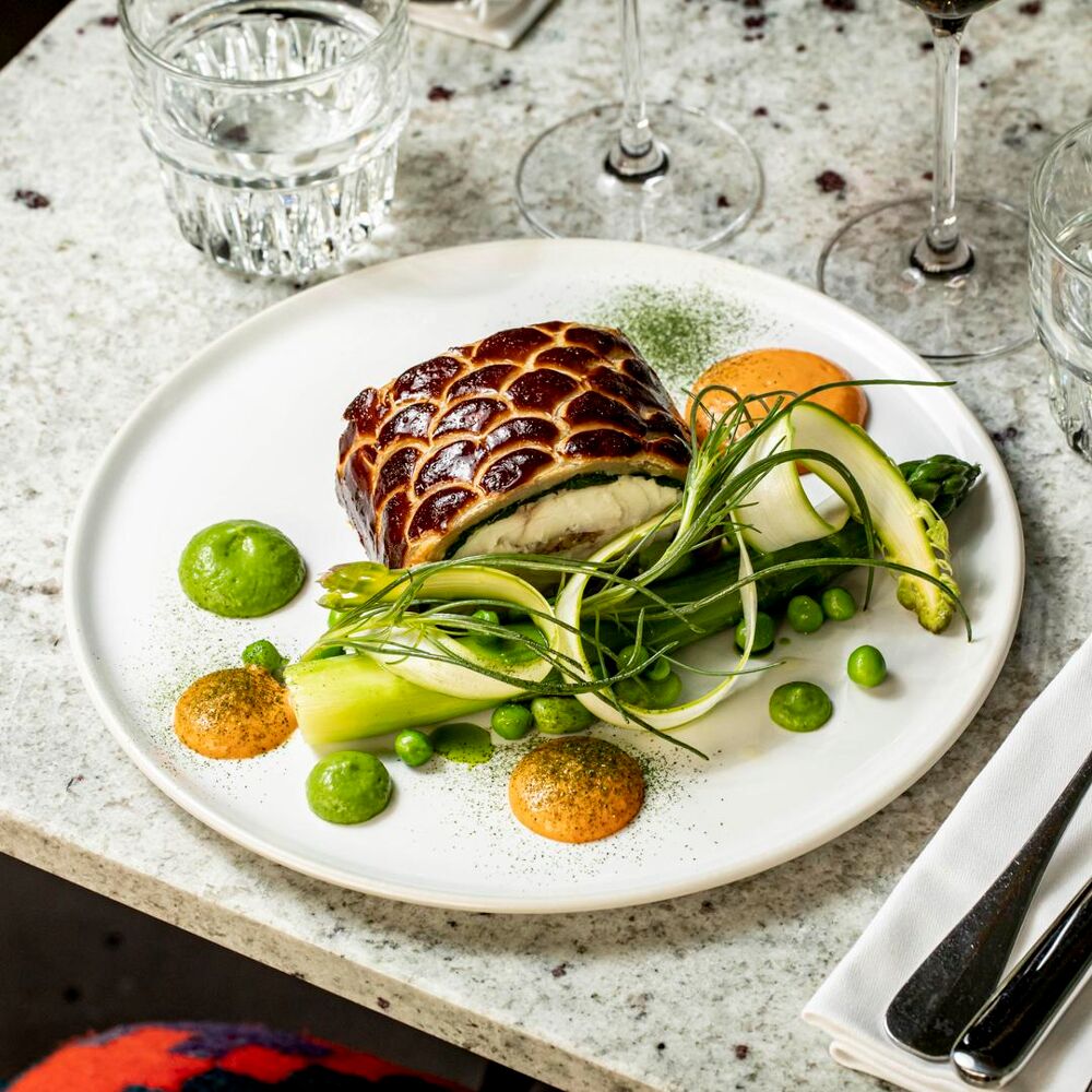 Plat gastronomique avec légumes et sauce colorée.