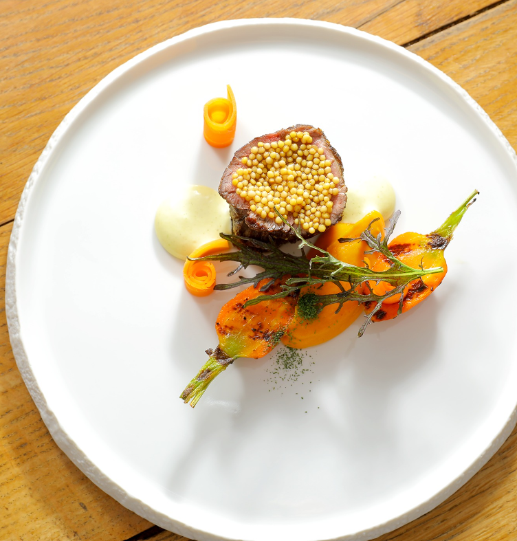 Plat gastronomique, carottes glacées et snackées, jeune pousse, pièce de bœuf rosée, graines de moutarde, carottes roulées et purée blanche crémeuse