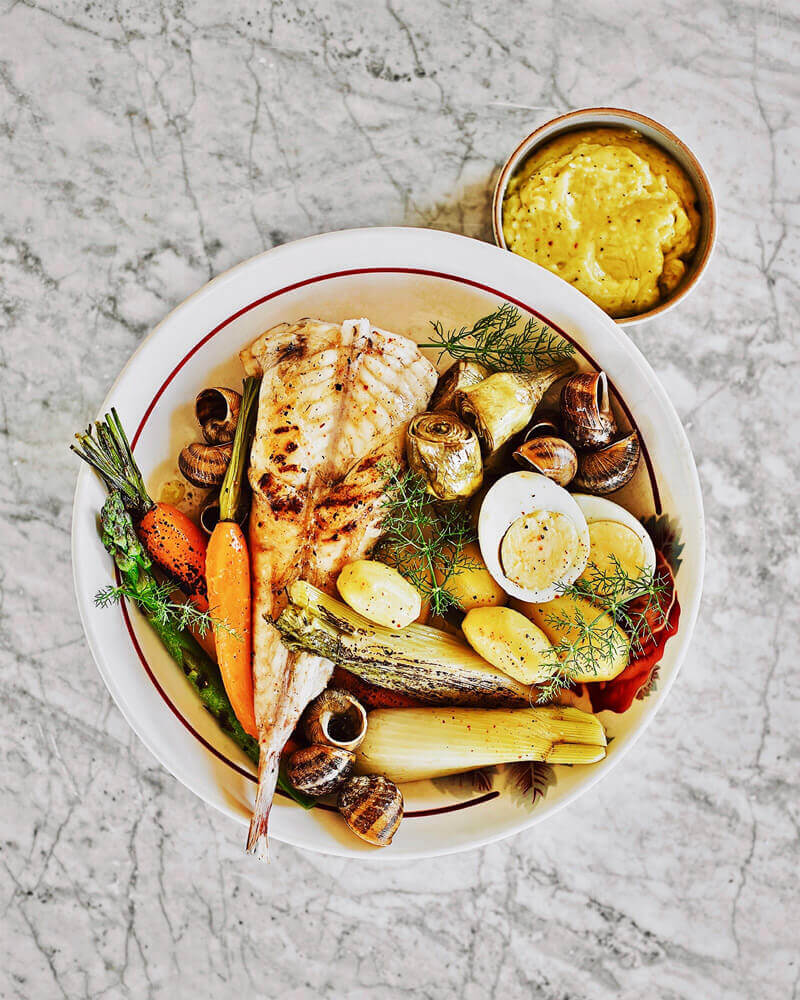 Plat de poisson grillé avec légumes et escargots.