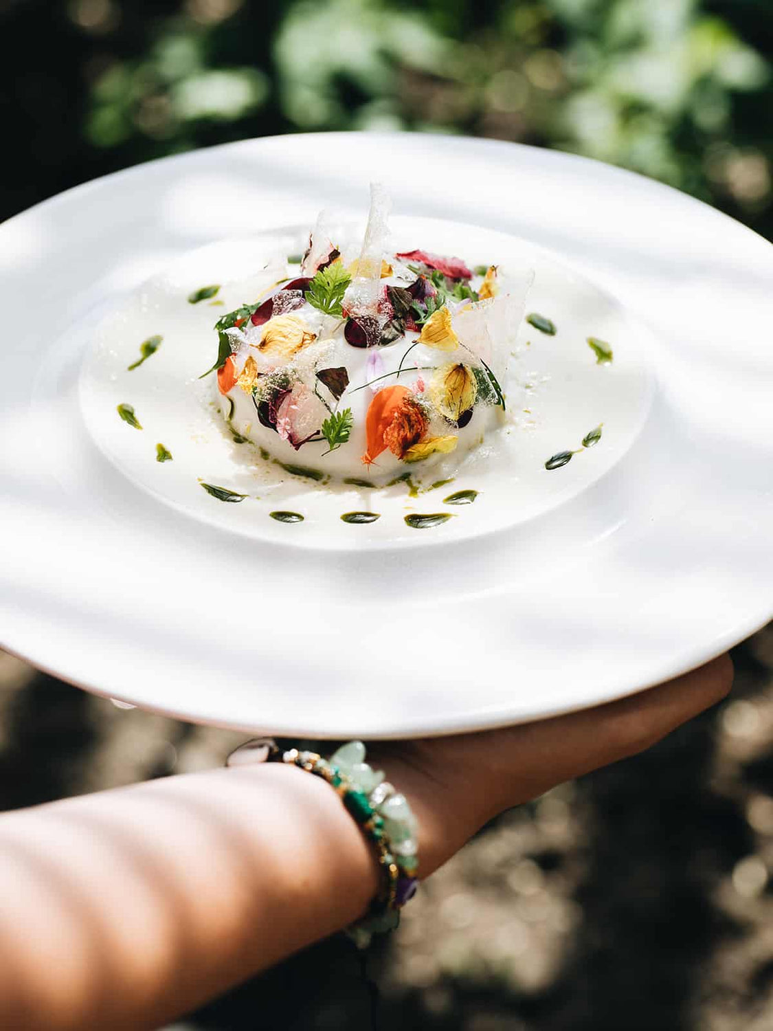 Assiette artistique avec préparation culinaire et fleurs comestibles en extérieur
