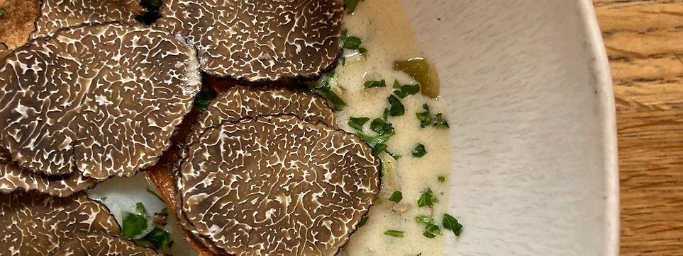 Truffle slices on creamy dish with herbs.