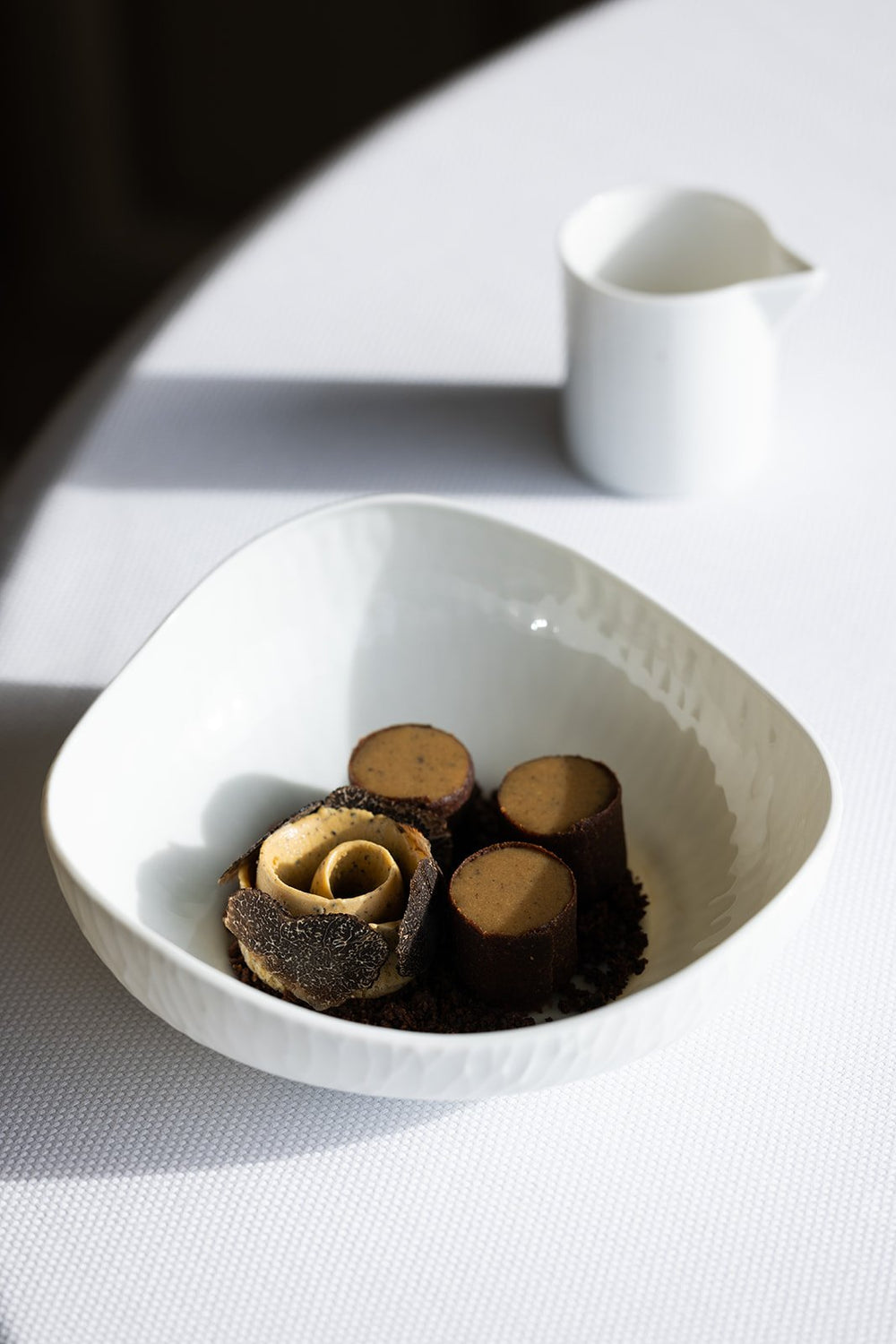 Dessert sophistiqué à base de truffe et chocolat, servi dans une assiette blanche élégante.
