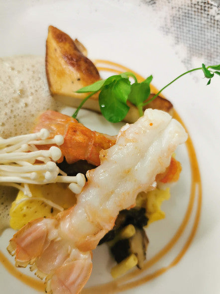 Plat de fruits de mer avec des légumes et une sauce mousseuse, présenté de manière artistique.