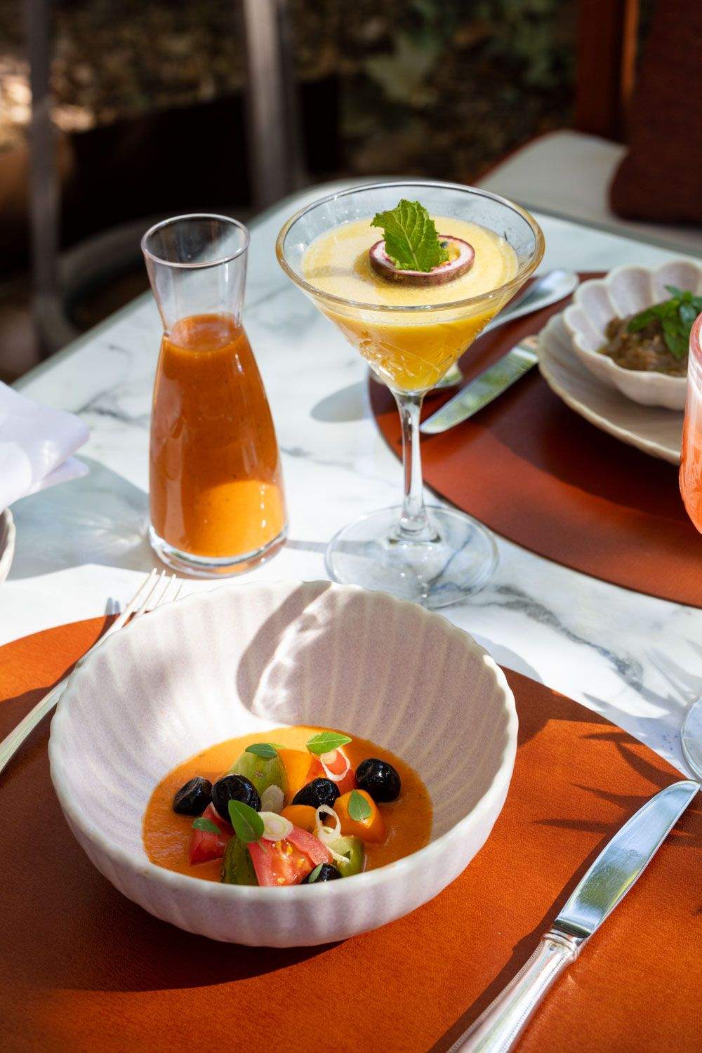 Plat gastronomique avec une présentation artistique et un cocktail, servi sur une table extérieure