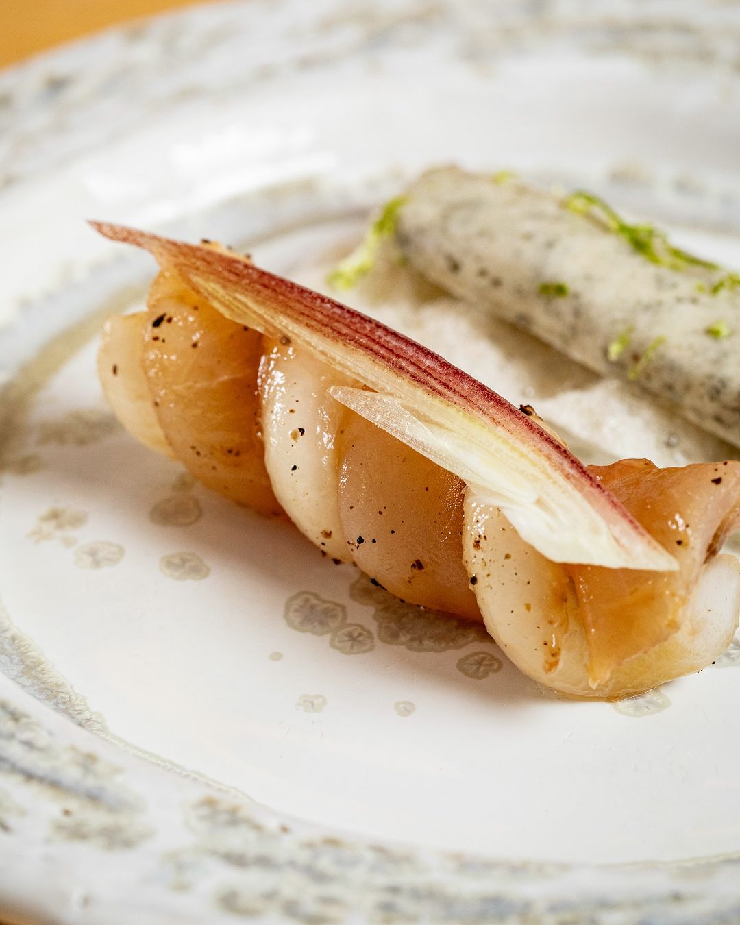 Plat raffiné avec des coquilles Saint-Jacques et des garnitures délicates, présenté sur une assiette blanche.