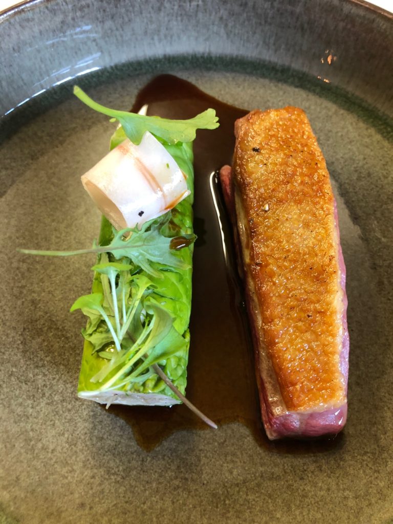 Plat gastronomique avec une pièce de viande grillée et des légumes verts, présenté sur une assiette grise
