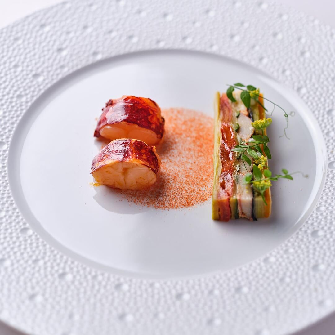 Plat de homard rôti accompagné d'un gratin de légumes finement disposé.